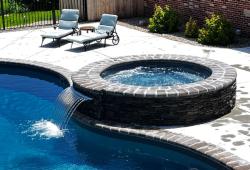 Inground spa with sheer descent water feature cascading into the pool 